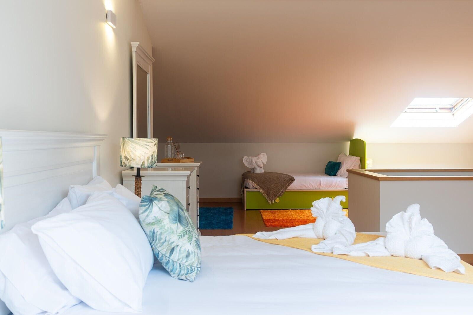 Une chambre à coucher avec un lit, une table de chevet avec une lampe, une commode, un petit bureau et une fenêtre.