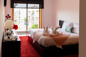 Une chambre d’hôtel avec un lit, une table de chevet, un tapis rouge et une vue sur les bâtiments par la fenêtre.