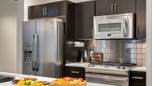 A modern kitchen with stainless steel appliances, dark cabinetry, and a white countertop. - 2-Storey PH Pano Views+2 Terraces|Parking|Soaker Tub (Calgary)