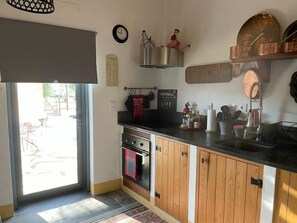A kitchen with wooden cabinets, a stove, a sink, and a window. - Holiday Home 'Herdade Da Carapuça' with Mountain View, Private Pool and Wi-Fi (Portalegre)