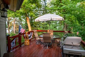 A wooden deck with outdoor furniture, including a table and chairs, and a grill.