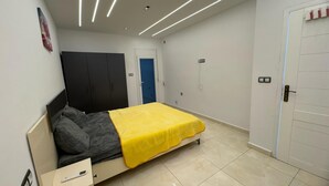 A bedroom with a bed, a wardrobe, a bedside table, and a door. - Villa with swimming pool 7mn from port Say (Marsa Ben M'Hidi)