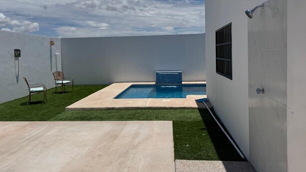 A modern outdoor pool area with a rectangular pool, a small waterfall feature, and two chairs. - House for 8 with Private Pool (San Carlos)