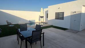 A patio with a table and chairs, a small pool, and a covered area with an umbrella. - House for 8 with Private Pool (San Carlos)
