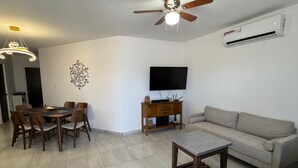 A living room with a dining table, chairs, a sofa, a TV, a ceiling fan, and an air conditioning unit. - House for 8 with Private Pool (San Carlos)