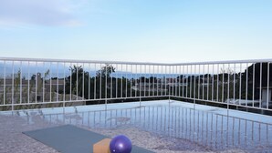 A balcony with a white railing, a yoga mat, and a purple exercise ball. - Stunning Seaview Apartment (Nea Makri)