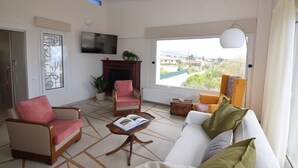 A living room with a sofa, two armchairs, a coffee table, a fireplace, and a TV. - Stunning Seaview Apartment (Nea Makri)