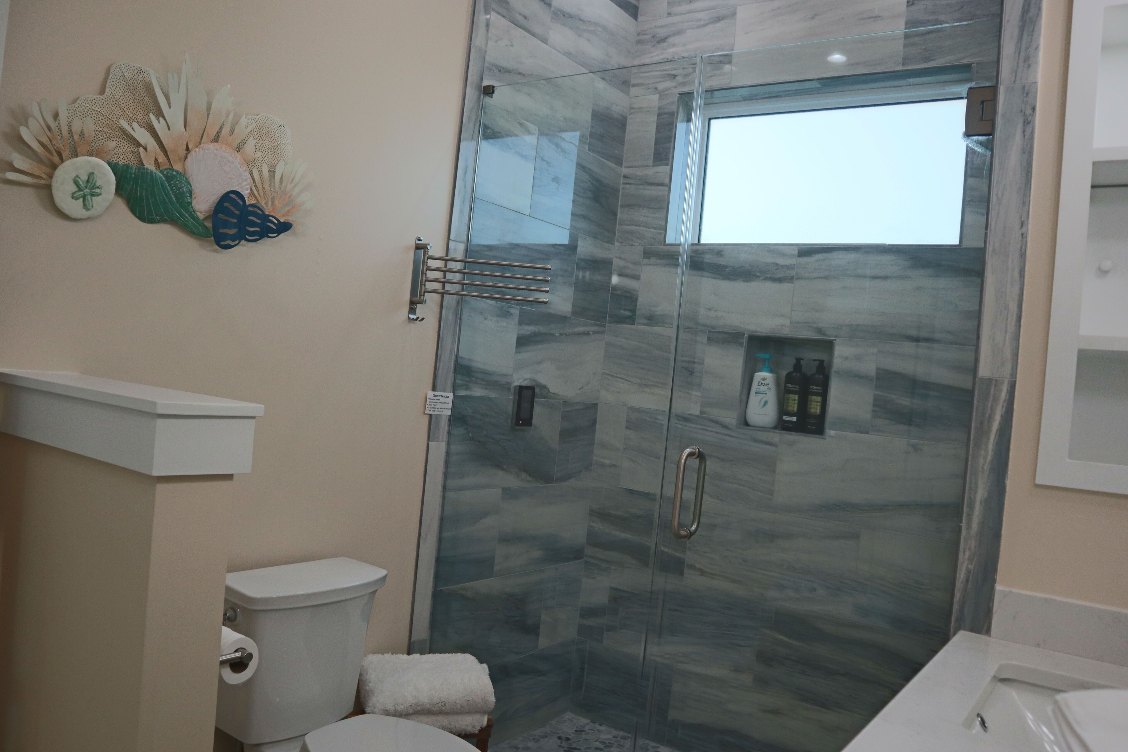 Een moderne badkamer met een glazen douchecabine, een toilet en een wastafel.