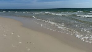 Een strand met heldere lucht en rustige golven.