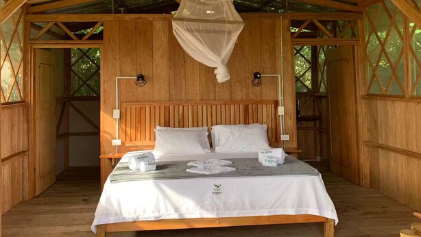 A wooden room with a bed, a nightstand, and a hanging mosquito net. - El Nido serene cabin with natural pool and chef #1 (La Macarena)