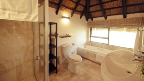 A bathroom with a bathtub, toilet, and a glass shower enclosure. - Luxury 3 Apartment (Sandton)