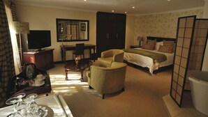 Ein Hotelzimmer mit einem Bett, einem Schreibtisch, einem Sessel, einem Fernseher und einem Schrank.