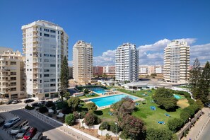 A high-rise residential building with a swimming pool and lounge chairs. - Gabriel 5 G Apartment with Sea View, Shared Pool and Wi-Fi (Armação de Pêra)