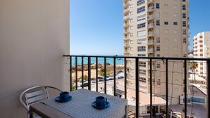 A balcony with a table and chairs, overlooking a cityscape and a body of water.