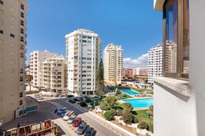 Un immeuble résidentiel de grande hauteur doté de nombreux balcons, d’une piscine et d’un espace de stationnement.