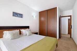 Une chambre d’hôtel avec un lit, une table de chevet, une armoire et un tableau encadré au mur.