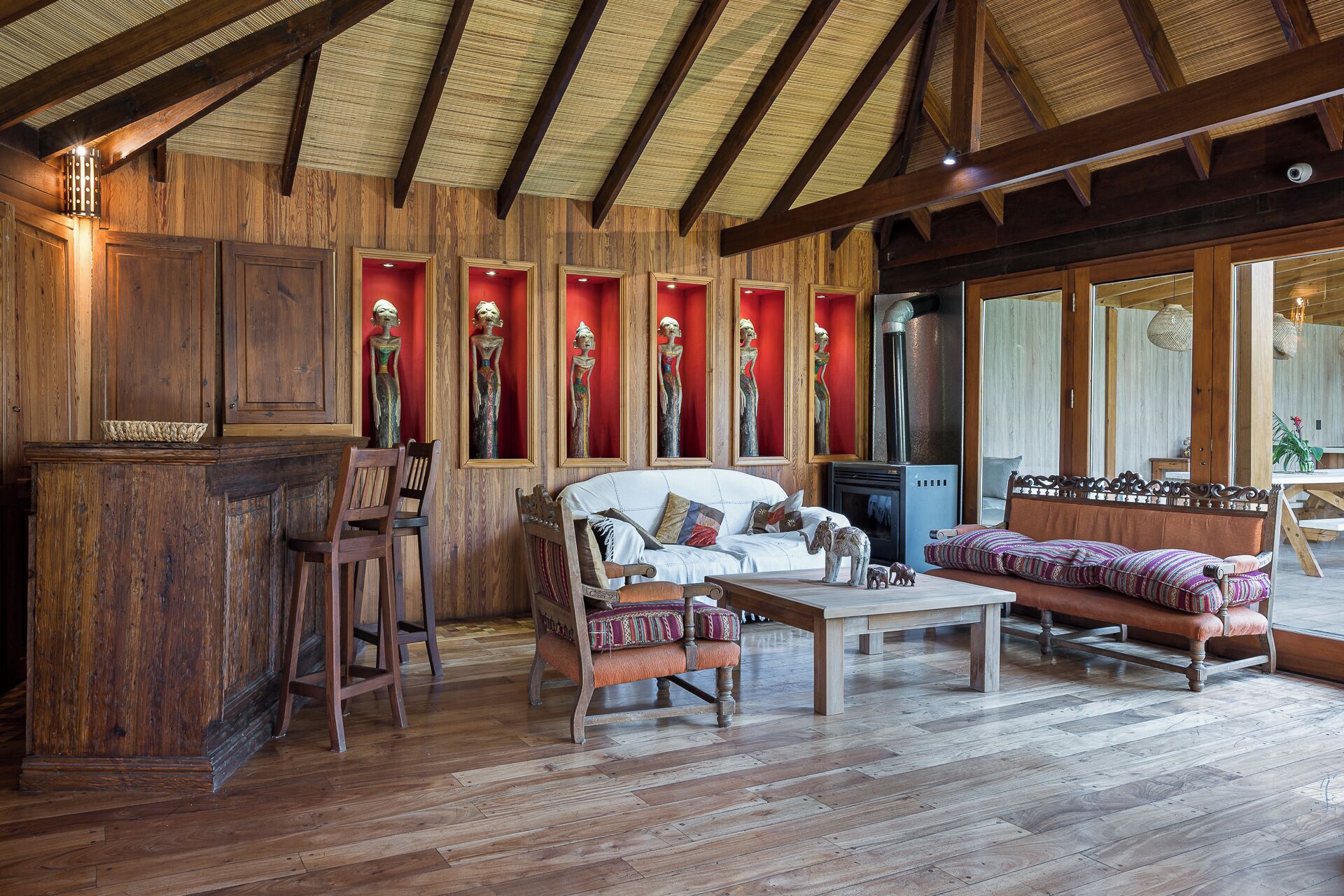 Un interior rústico con paredes de madera, un sofá blanco, una mesa de centro de madera y un espejo con marco rojo.