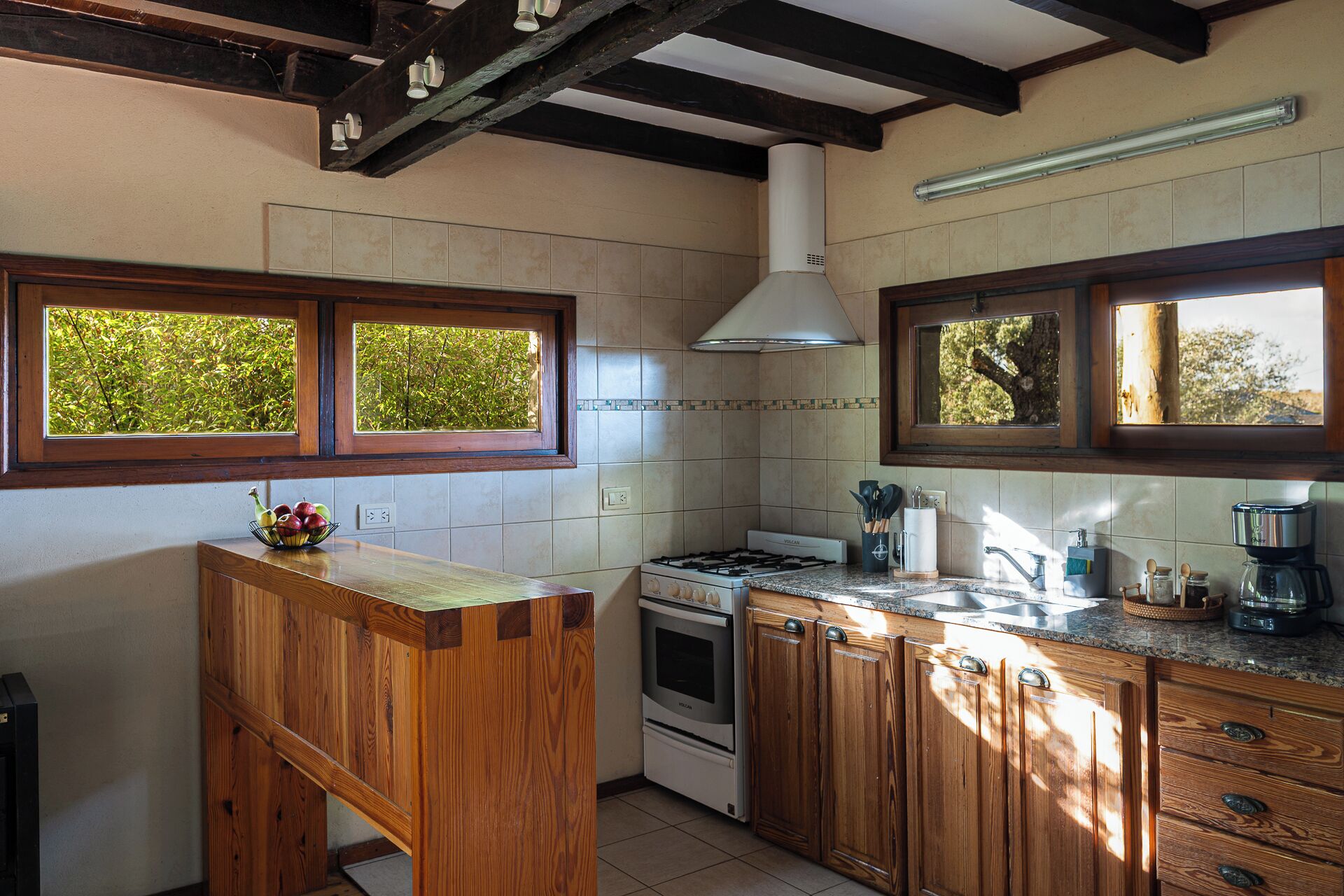 Eine Küche mit Holzausstattung, einem Gasherd, einem Backofen und einem Fenster mit Blick auf Bäume.
