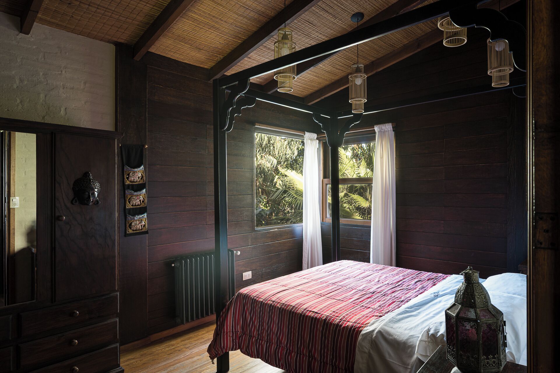 A room with a bed, a radiator, a wooden door with a decorative handle, and a window with curtains.