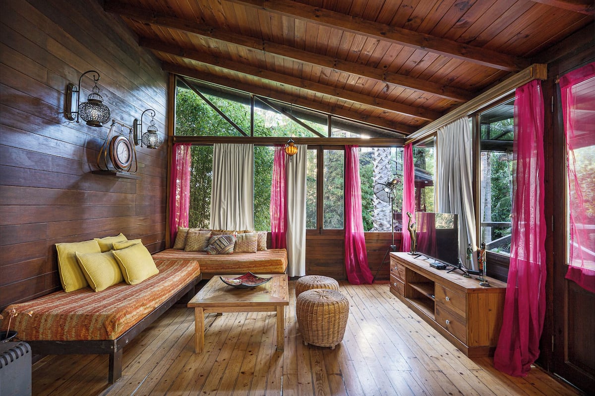 A cozy cabin interior with a wooden floor, a sofa, a coffee table, and a television.