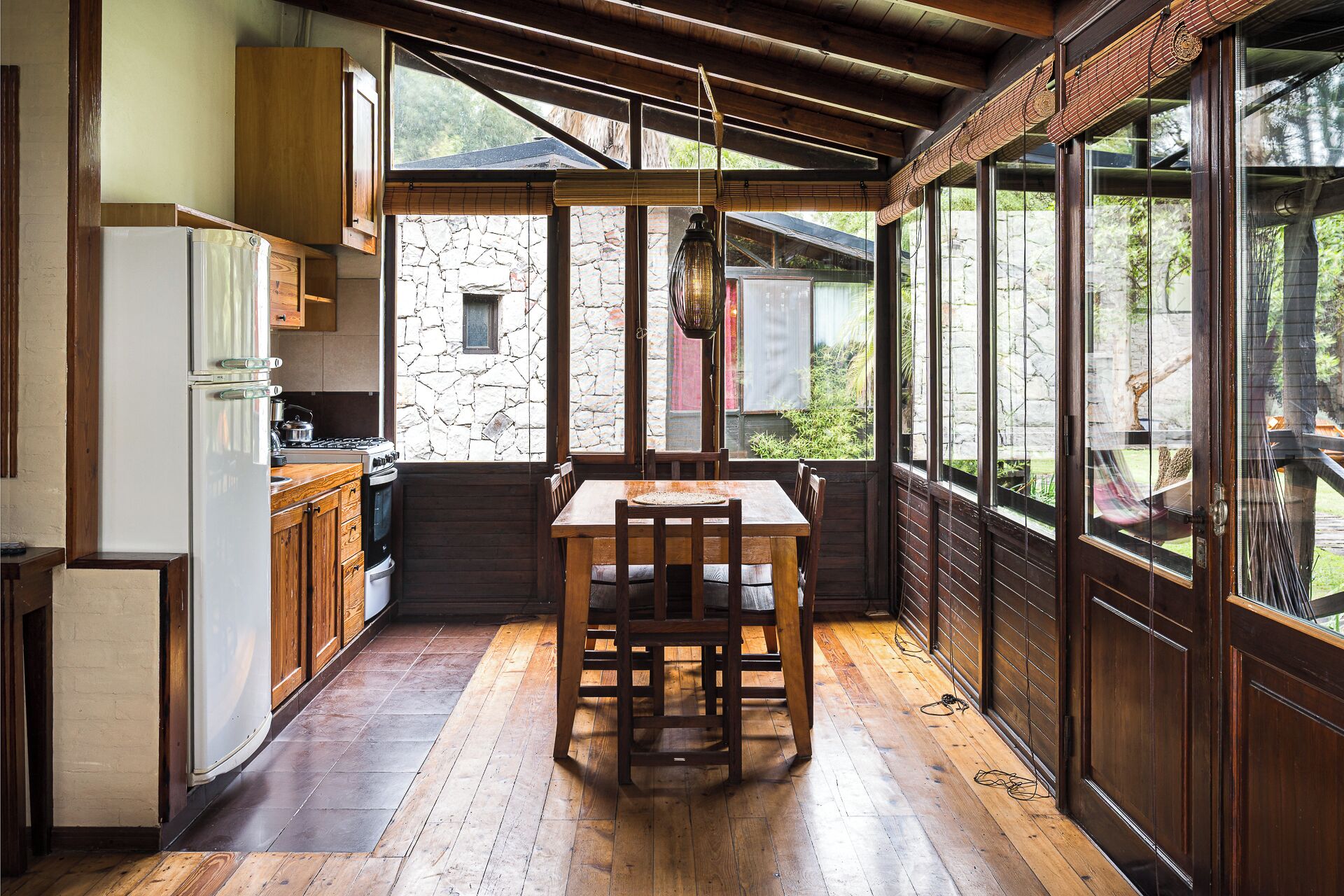 A kitchen with wooden cabinets, a dining table, and a stone wall.