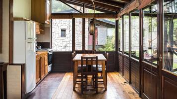 A kitchen with wooden cabinets, a dining table, and a stone wall.