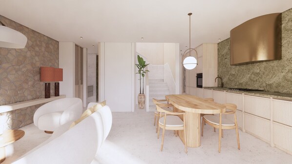 A modern kitchen with a wooden dining table and chairs, a stone wall, and a staircase leading to another level.