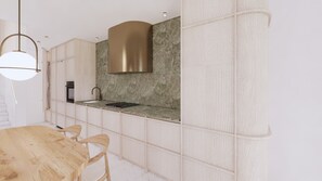 Une cuisine moderne avec un dosseret en marbre, une hotte en acier inoxydable et une table à manger en bois avec des chaises.