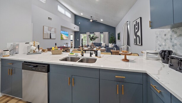 A modern kitchen with grey cabinetry, a dishwasher, and a large island with a sink.