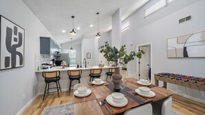 A modern kitchen with a dining area, wooden table, chairs, and a foosball table.