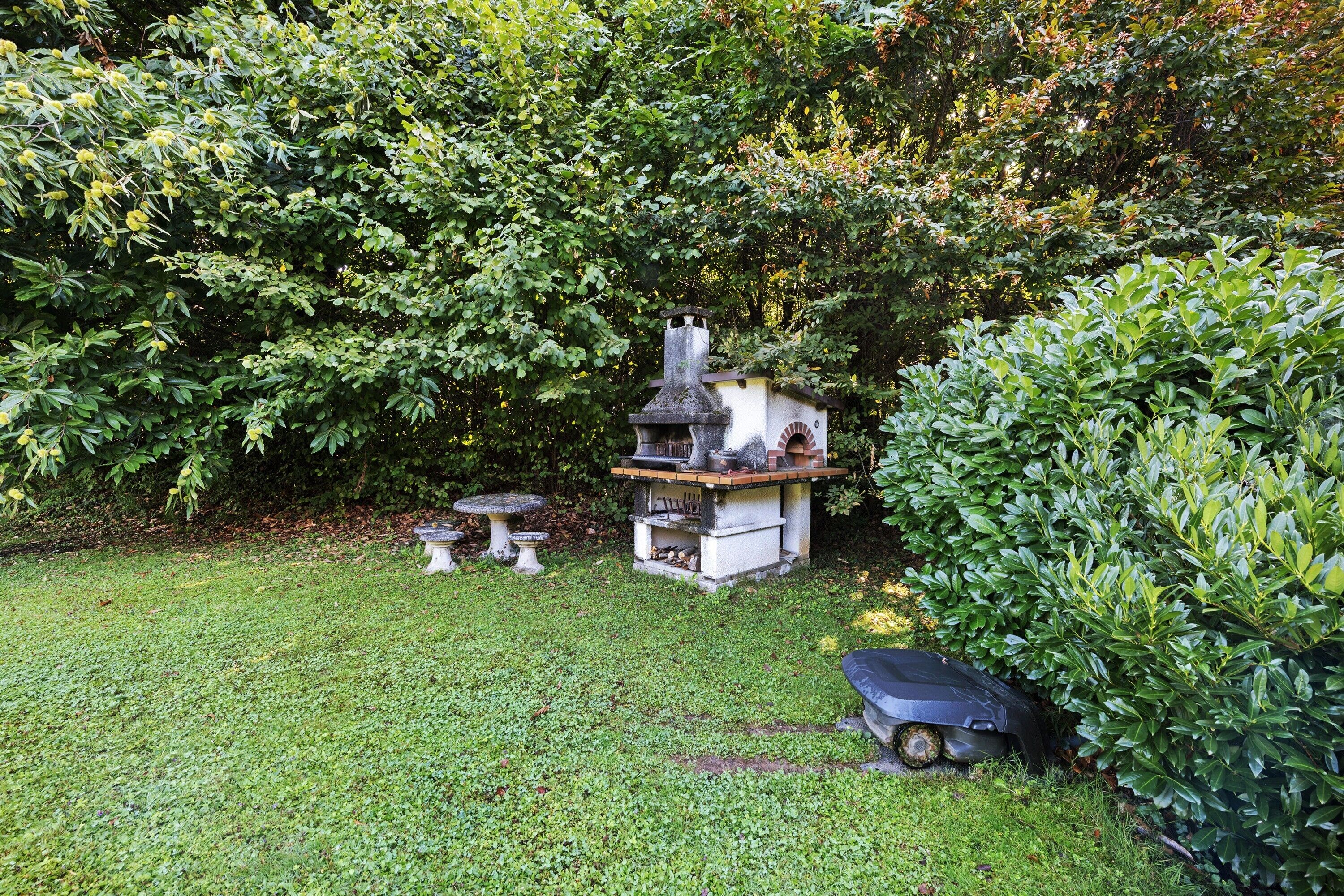 A garden with a birdhouse, a small table, and a chimney structure.