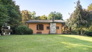 A house with a stone chimney, a small porch, and a well-maintained lawn.