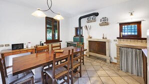 A dining area with a wooden table and chairs, a microwave, and a fireplace.