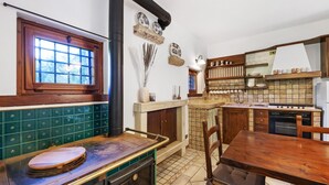 A kitchen with a wood stove, a dining table, and a built-in oven.