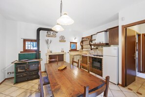 Une cuisine avec une table en bois, des placards, une cuisinière et un réfrigérateur.