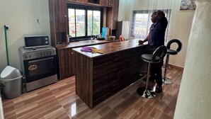 A modern kitchen with wooden cabinets, a built-in microwave, and a large island with bar stools. - 3rd floor (Conakry)