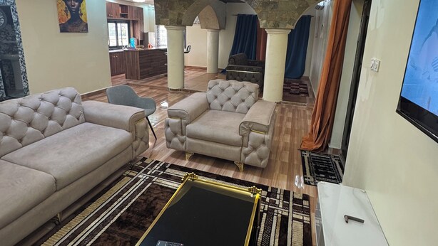 A modern living room with a sofa, armchairs, a coffee table, and a TV. - 3rd floor (Conakry)