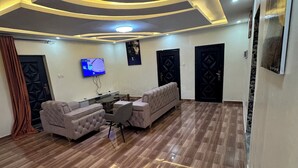 A modern living room with a sofa set, a coffee table, and a flat-screen TV mounted on the wall. - 3rd floor (Conakry)