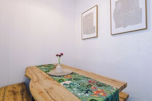 A wooden table with a floral tablecloth, a vase with flowers, and two framed artworks on the wall. - 2 Bed apartment| sleeps up to 5| (Blackpool)
