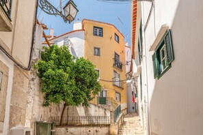 Una calle estrecha con edificios, un árbol y una escalera.