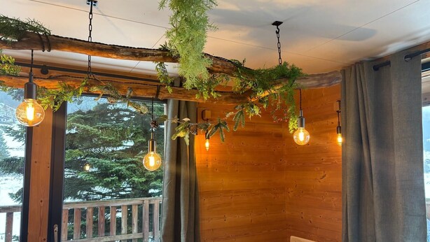 A cozy room with wooden walls, a wooden ceiling, and a view of a snowy deck outside.