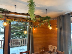 A cozy room with wooden walls, a wooden ceiling, and a view of a snowy deck outside.