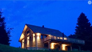 A wooden house with a balcony, surrounded by trees.