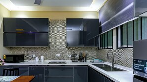 Une cuisine moderne avec des meubles de couleur sombre, un pare-feu en carreaux, un four à micro-ondes, une machine à café et un évier.