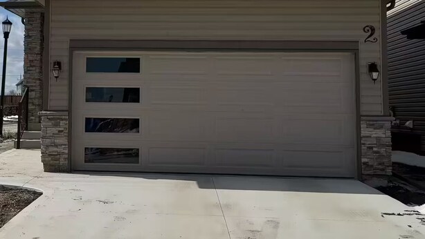 A two-story house with a garage, stone accents, and a clear blue sky. - Amazing 2-Bedroom Basement Suite (Winnipeg)
