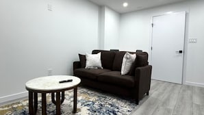 A living room with a brown sofa, a round coffee table, and a patterned rug. - Amazing 2-Bedroom Basement Suite (Winnipeg)