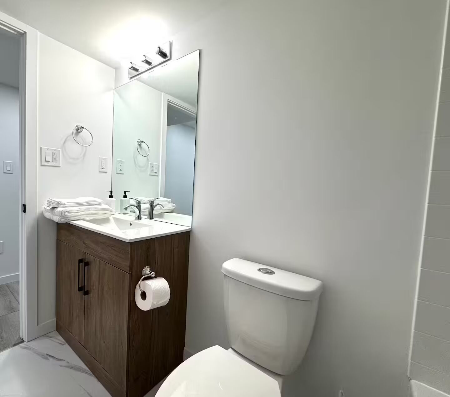 A modern bathroom with a white sink, mirror, and toilet.