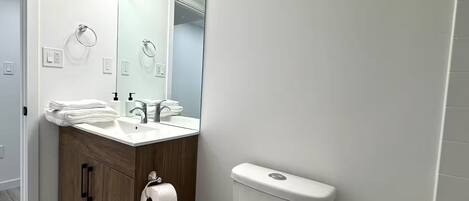 A modern bathroom with a white sink, mirror, and toilet.