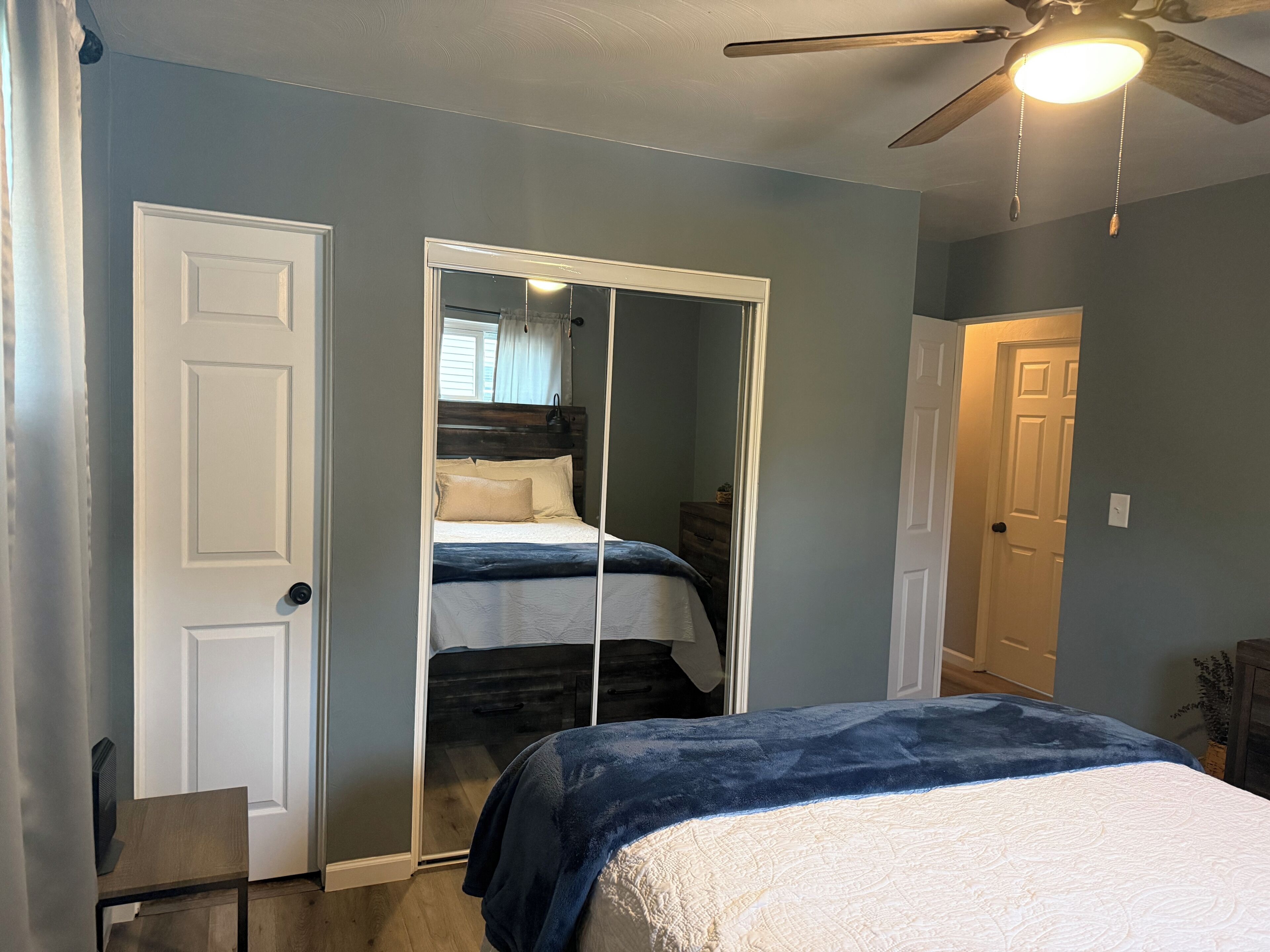 A bedroom with a bed, a wardrobe, and a ceiling fan.