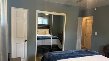 A bedroom with a bed, a wardrobe, and a ceiling fan.